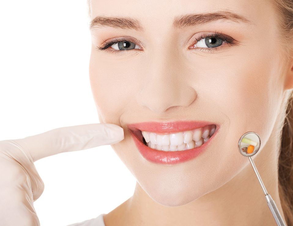 Young doctor or dentist with dental mirror and glove pointing on